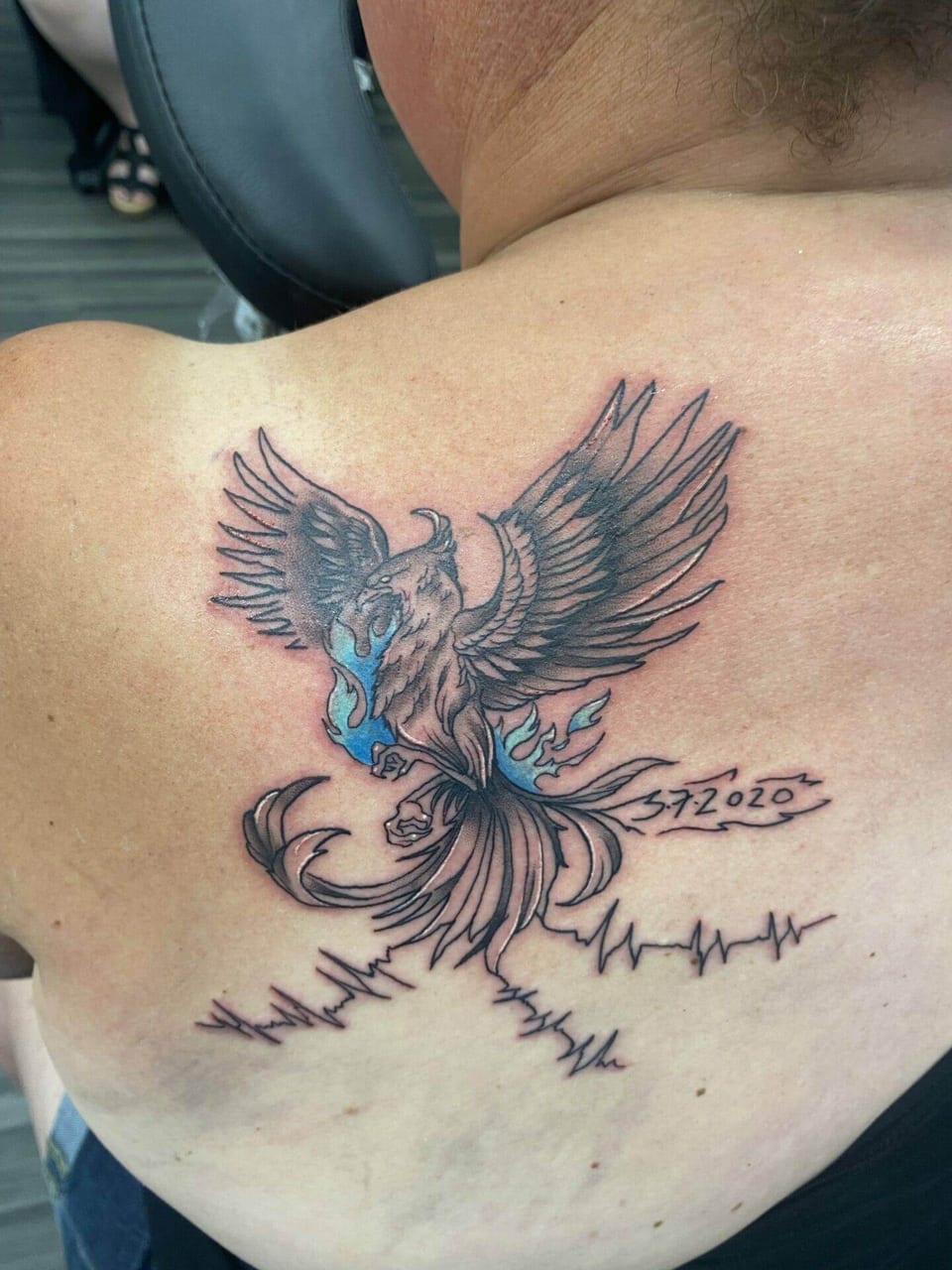 An illustrative phoenix with blue flames and heartbeat lines sits on the upper back.