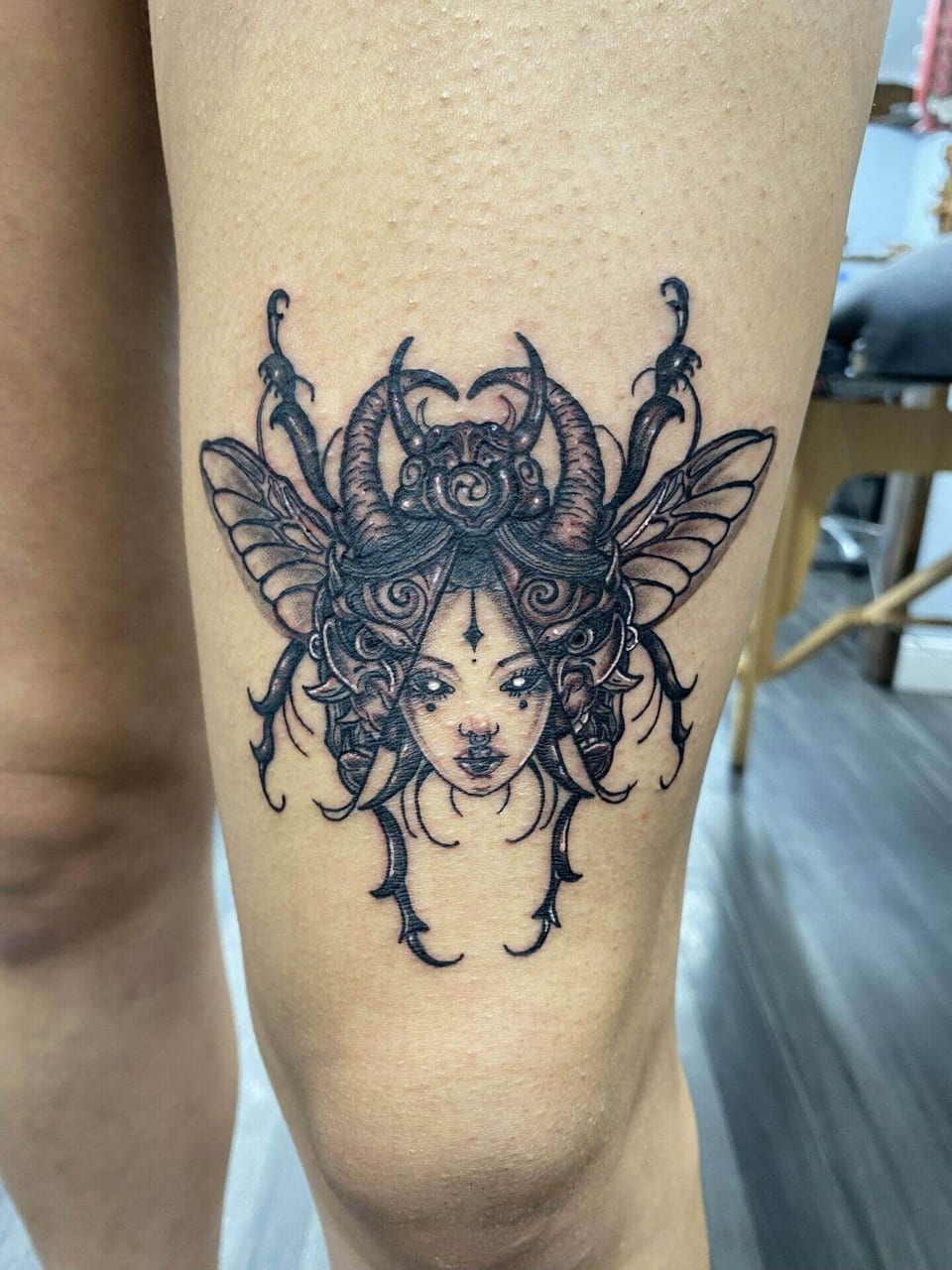A black illustrative woman's face merges with a horned beetle above a knee.