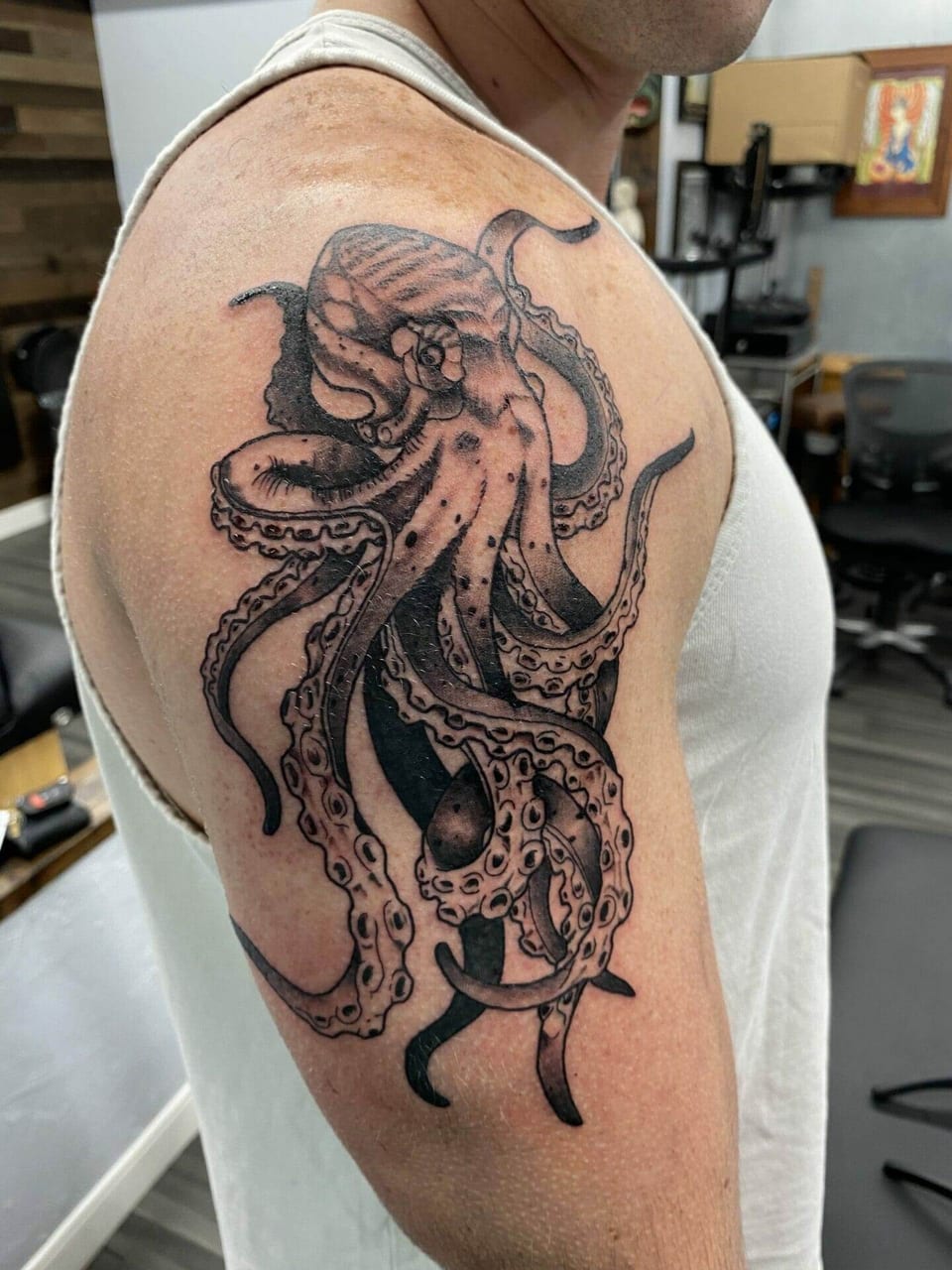 A black and grey illustrative octopus wraps across a shoulder and upper arm.