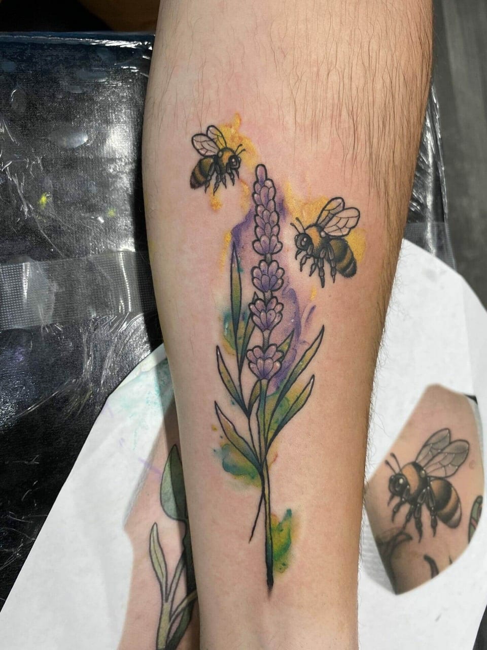 Watercolor lavender and bees run along an inner forearm.