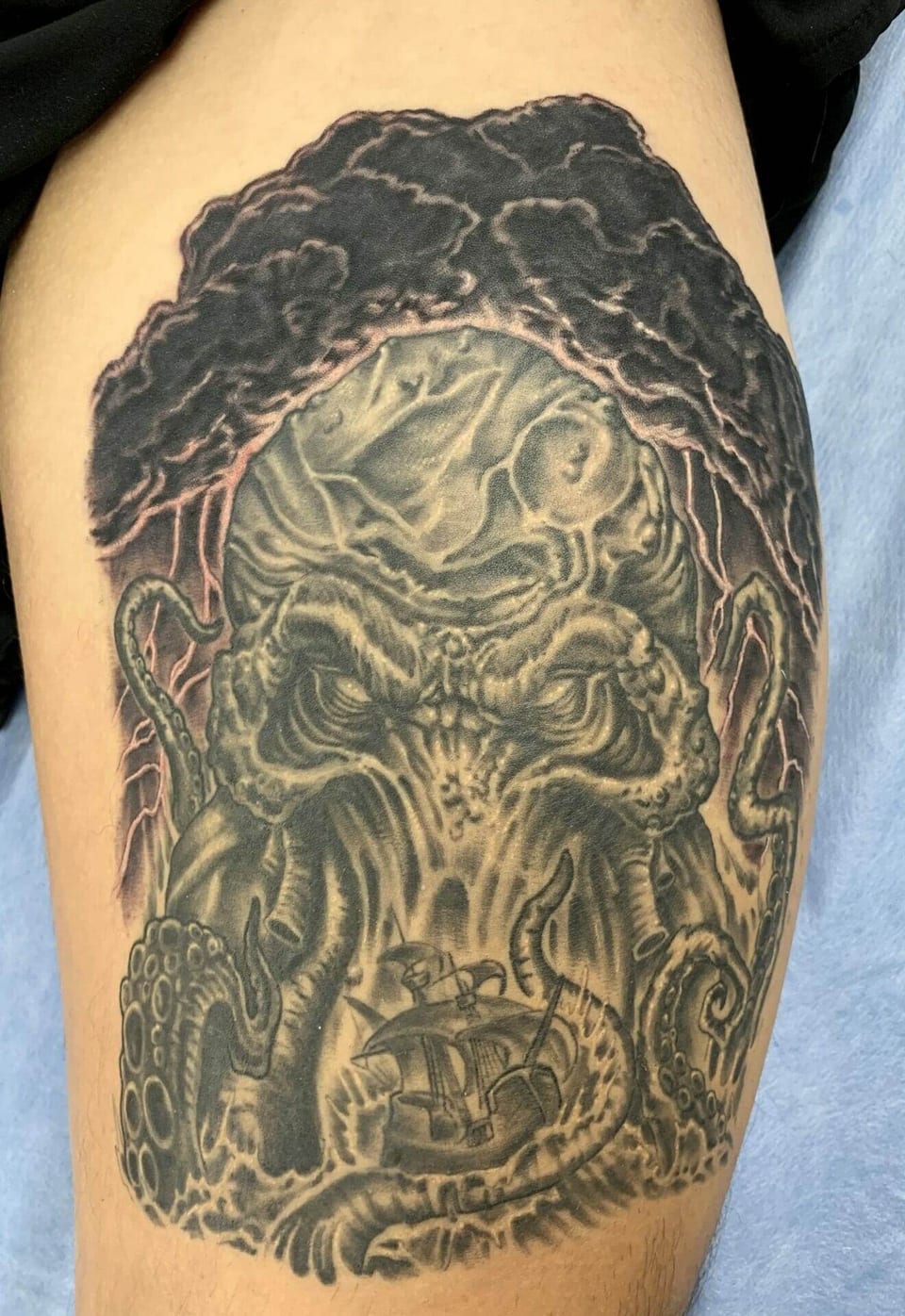A black and grey tentacled creature and sailing ship cover the thigh.