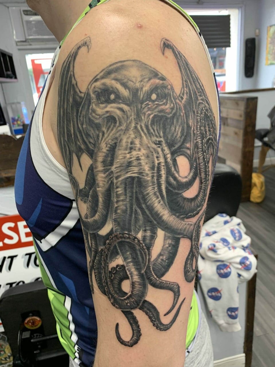 A black and grey winged tentacled creature covers the upper arm.