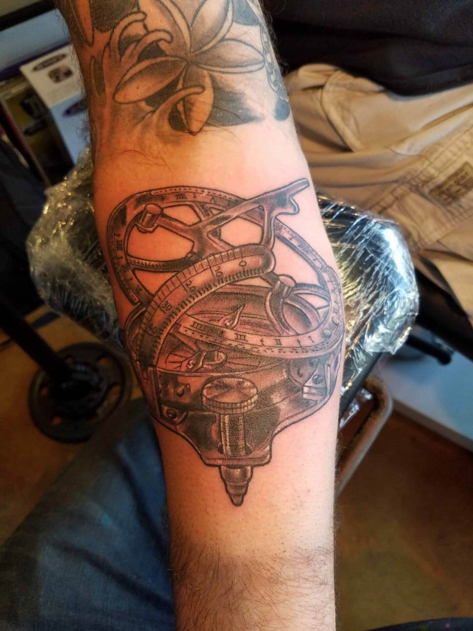 A black and grey measuring instrument with curved scales sits on the forearm.