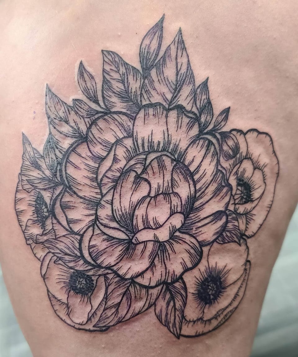 Black linework peony petals, smaller flowers and leaves form a back tattoo.