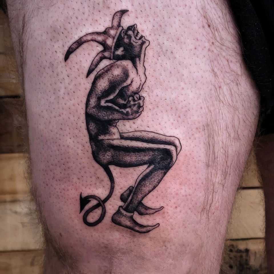 A black and grey horned devil crouches with clasped hands and a curled tail on the thigh.