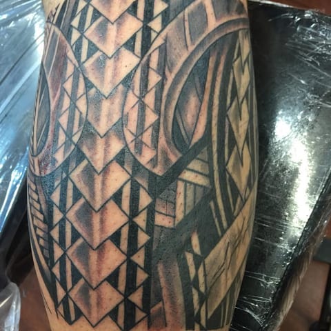 Black Polynesian bands with chevrons, triangles and curved motifs wrap around a calf.