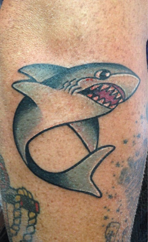 A traditional blue-grey shark with open jaws and a curled tail covers the thigh.