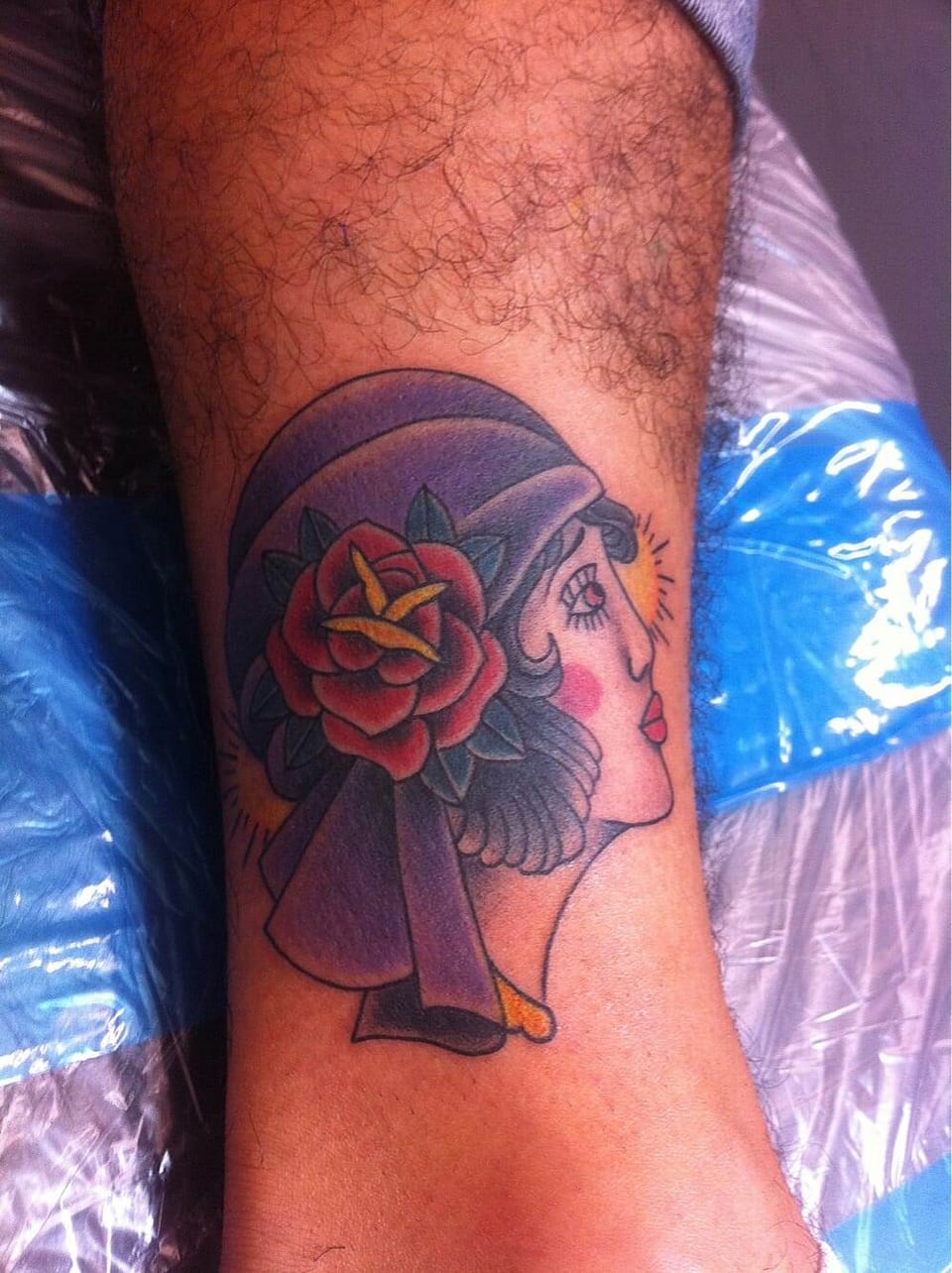 A traditional woman's profile in a purple headscarf with a red rose covers the lower leg.