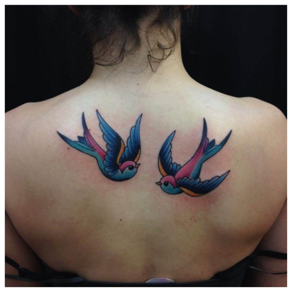 Traditional blue and red swallows face each other across the upper back.