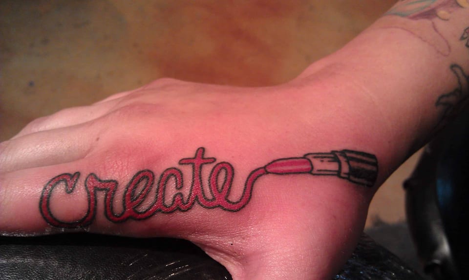 Red script reading Create flows into a paintbrush along the side of the hand.