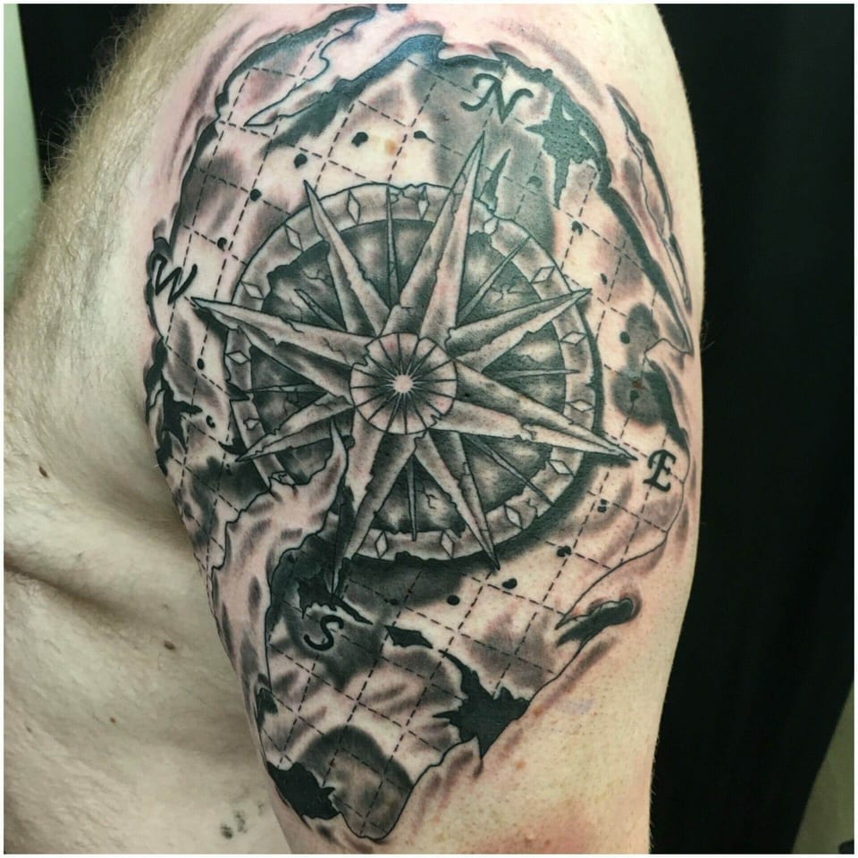 A black and grey compass rose overlays a map on the shoulder and upper arm.