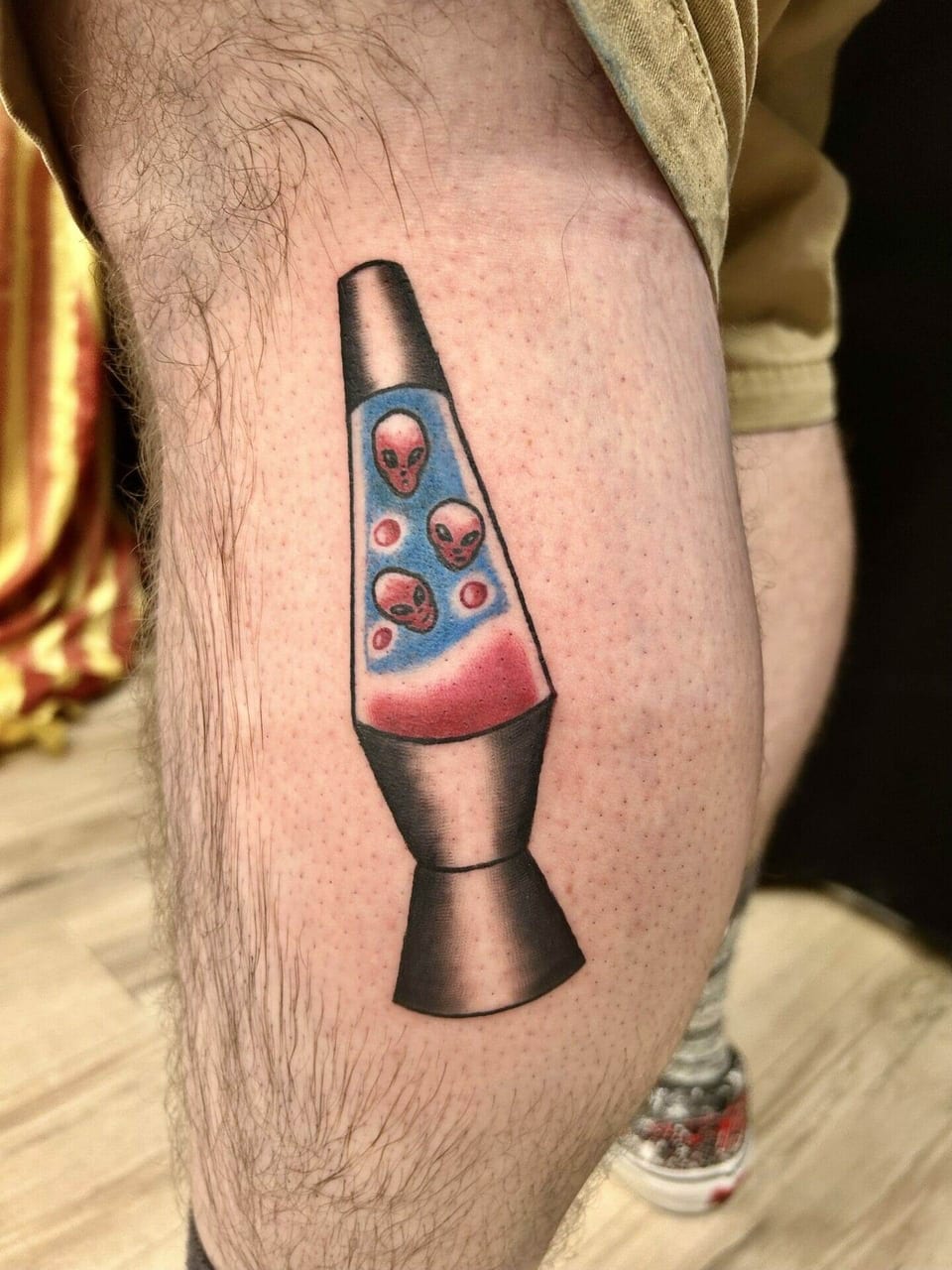 A color illustrative lava lamp contains red alien heads floating in blue liquid on a calf.