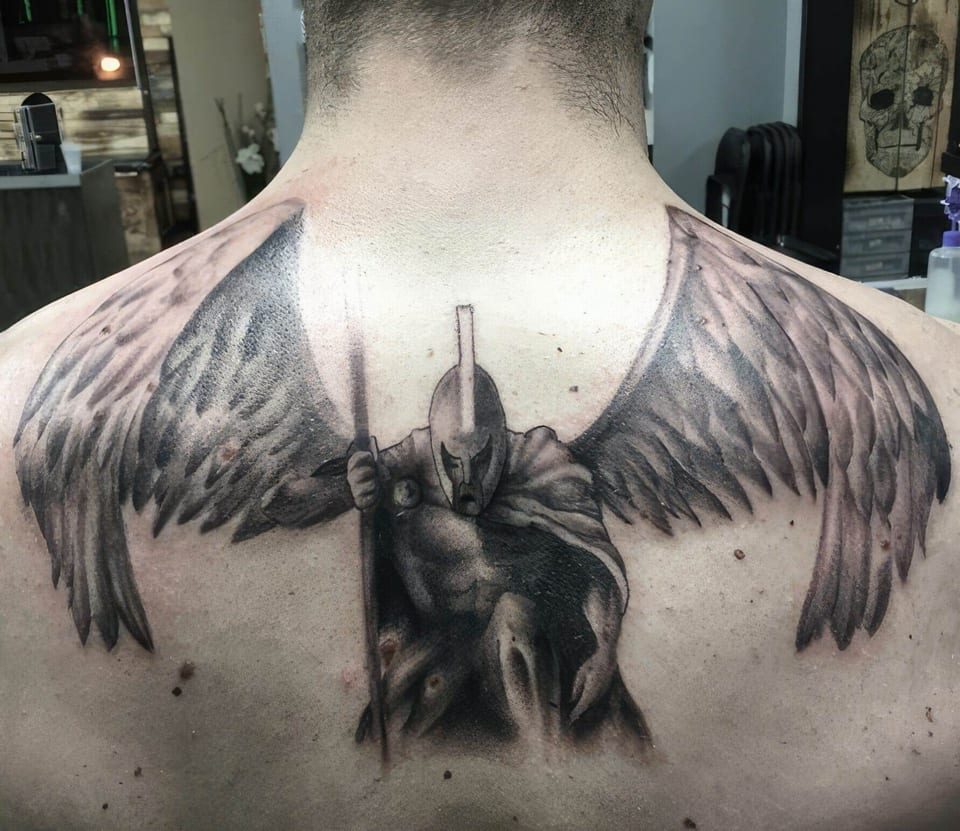 A black and grey helmeted warrior holds a spear beneath wings spread across the upper back.