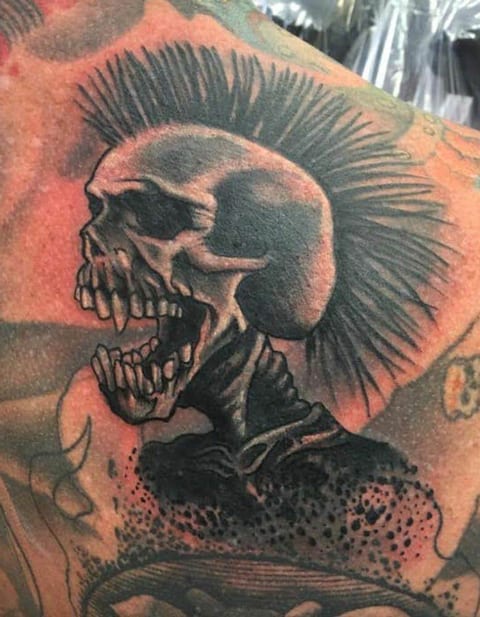 A black and grey skull with a tall mohawk appears in a tattoo.