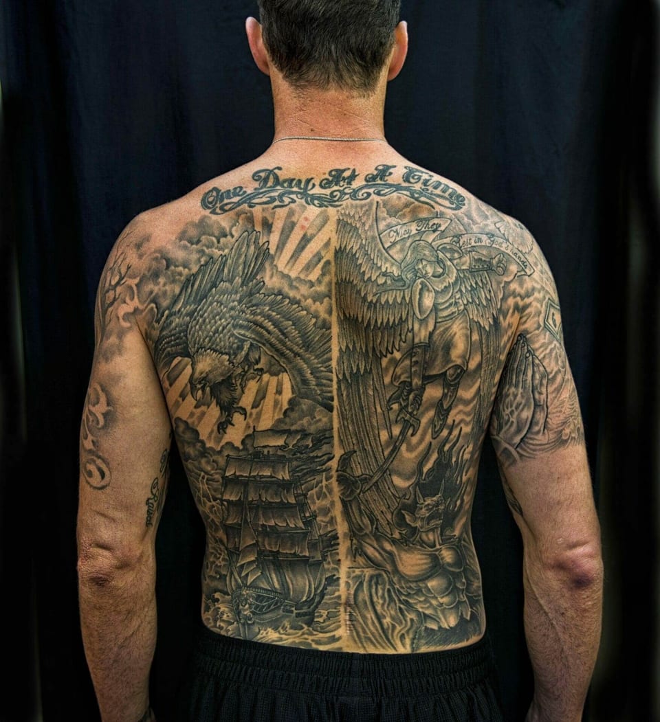A black and grey eagle, ship, winged warrior and demon cover the back beneath ornate lettering.