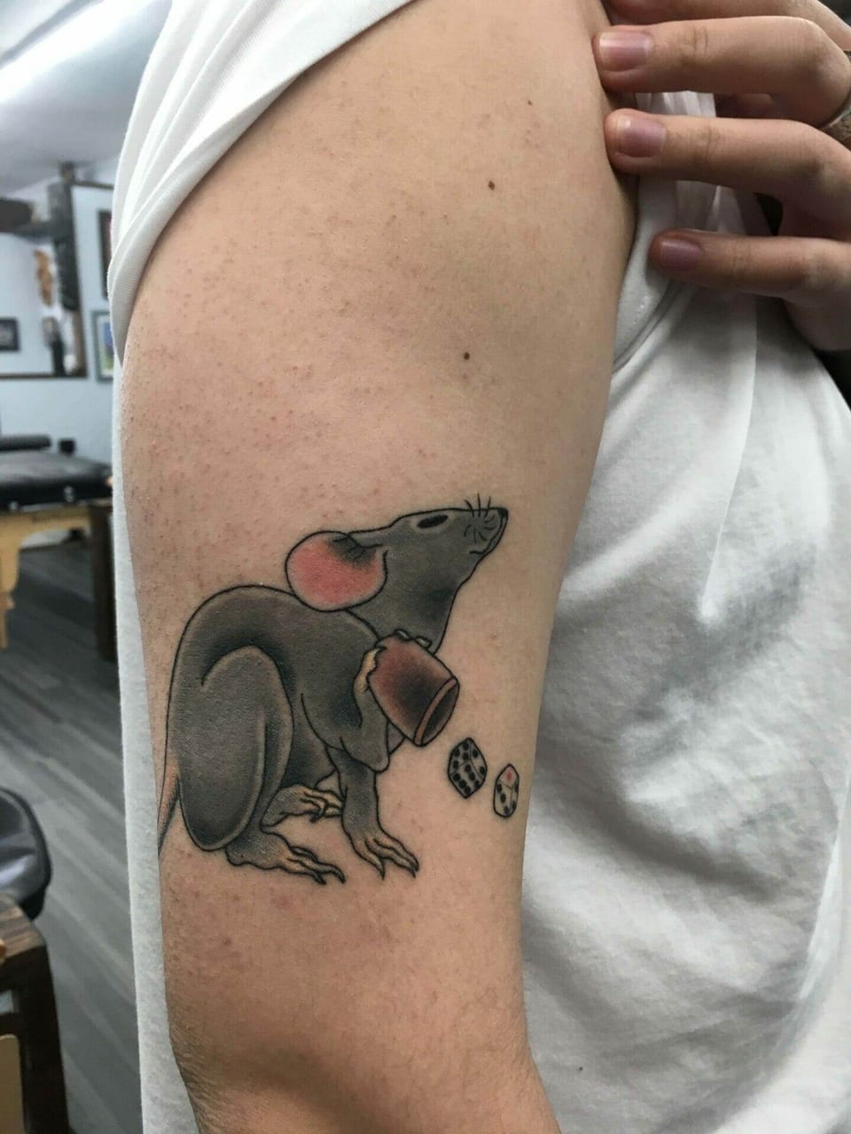 A traditional grey rat holds a cup beside dice on the upper arm.