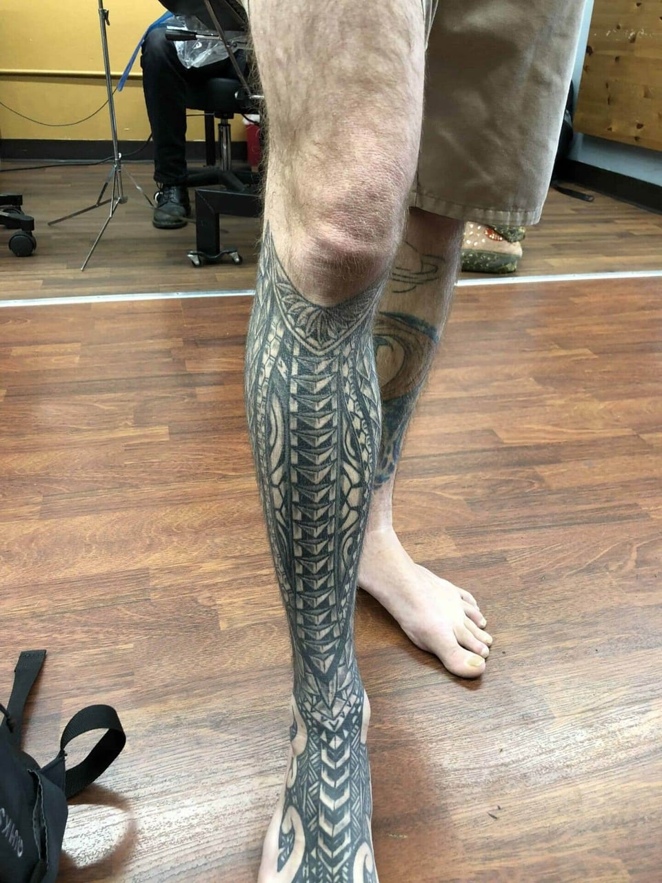 Polynesian pattern wrapping a man's lower leg, tattooed by Seth Reynolds