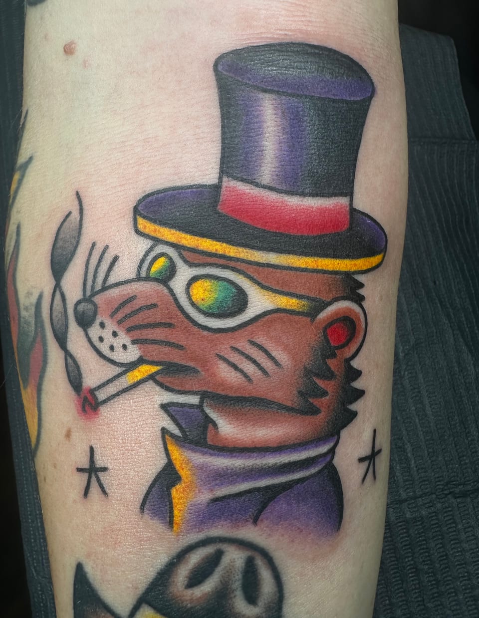 A brown rat tattoo wears a purple top hat and smokes a cigarette.