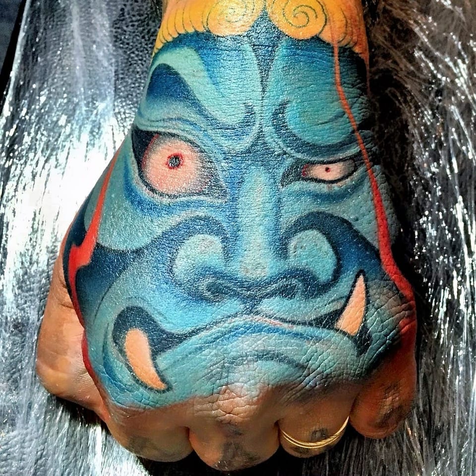 A color Japanese blue mask covers the back of a hand.