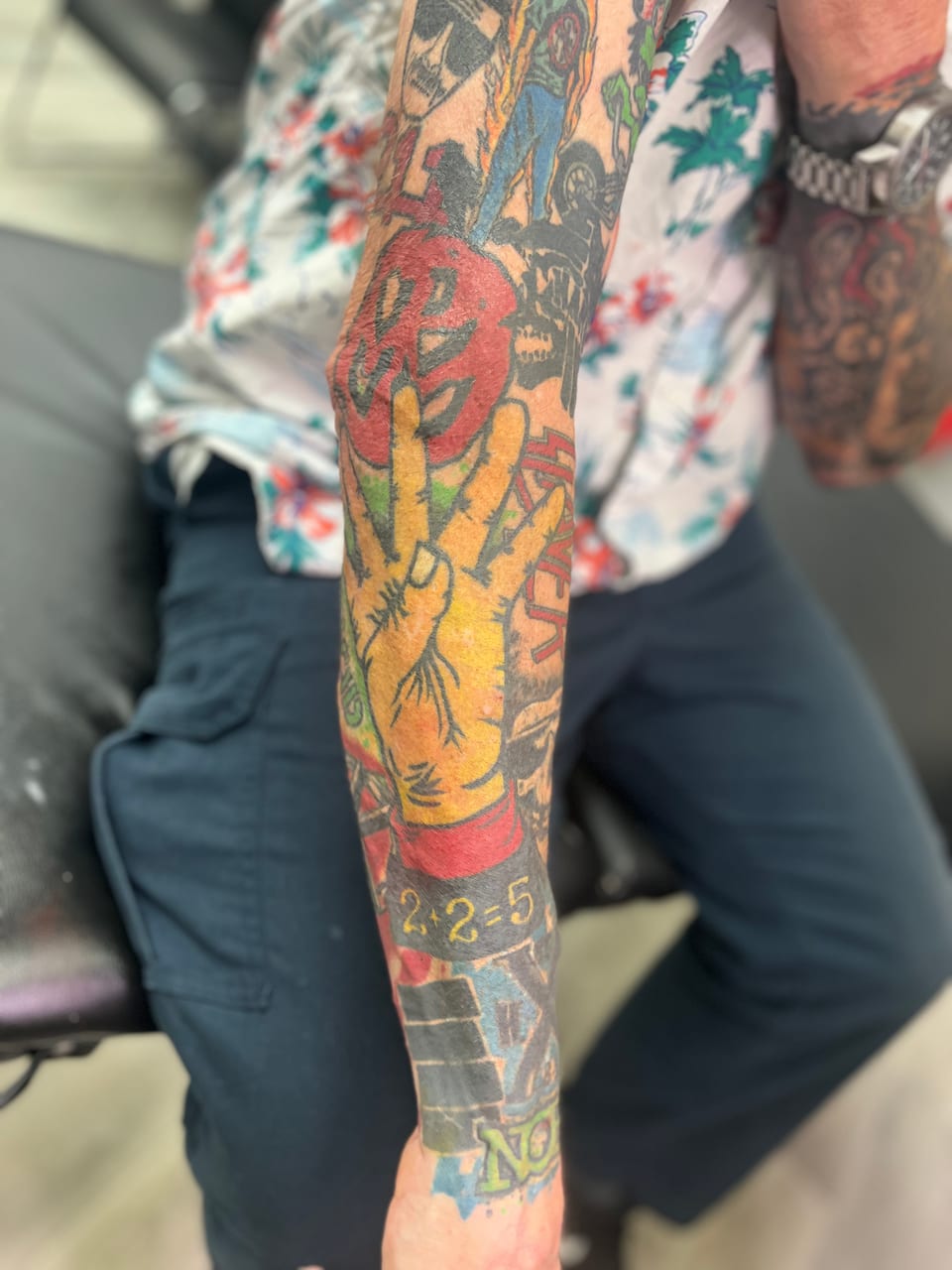 Tattooed arm with a peace sign, red and yellow colors.