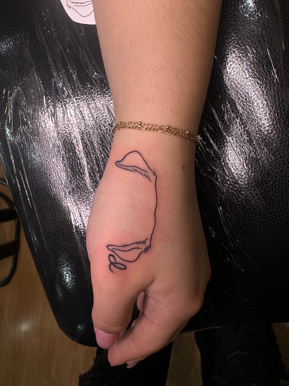 A fine-line outline of a face runs from the wrist onto the back of the hand.