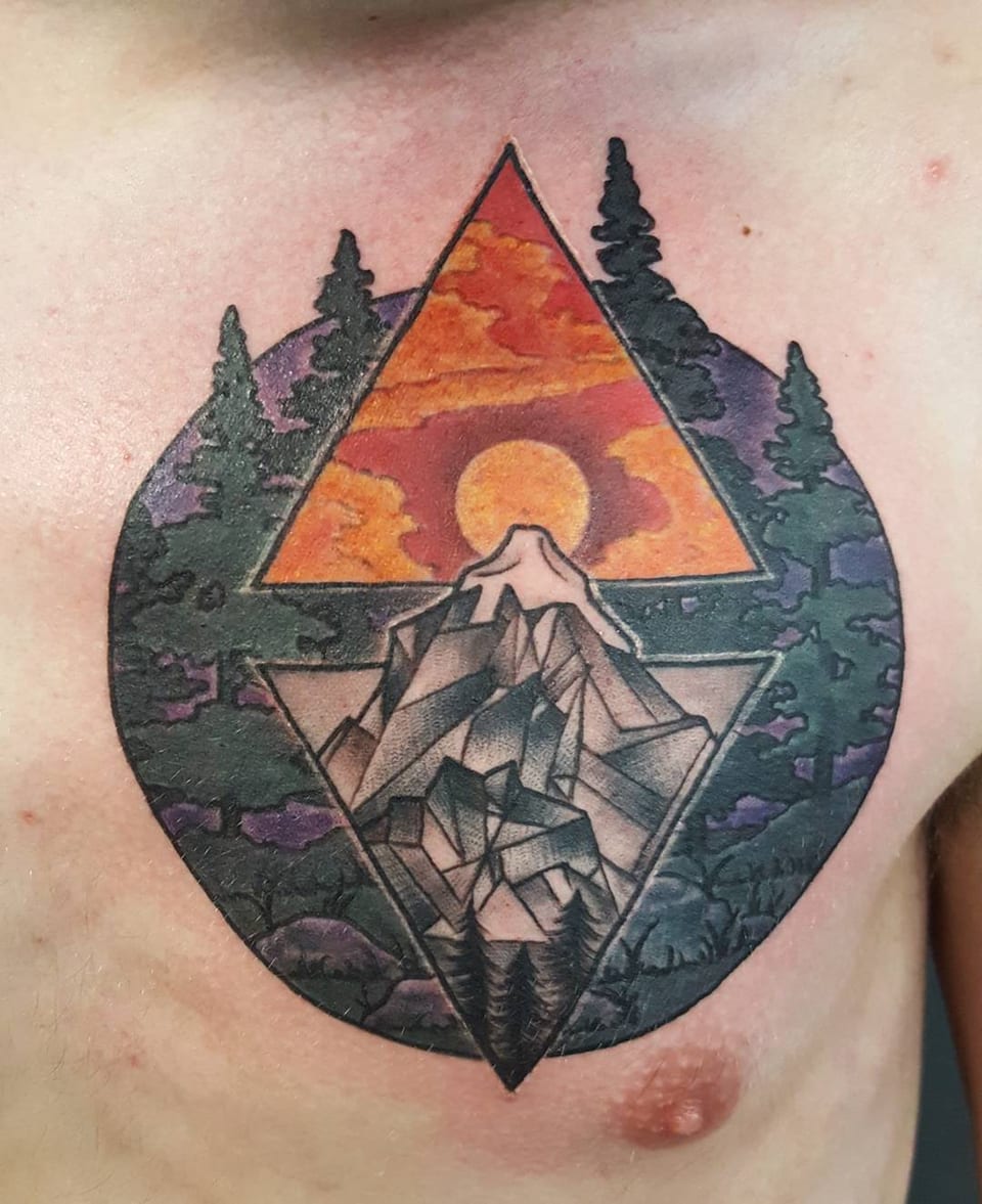 A colorful geometric mountain, pine trees and sunset tattoo sits on the chest.