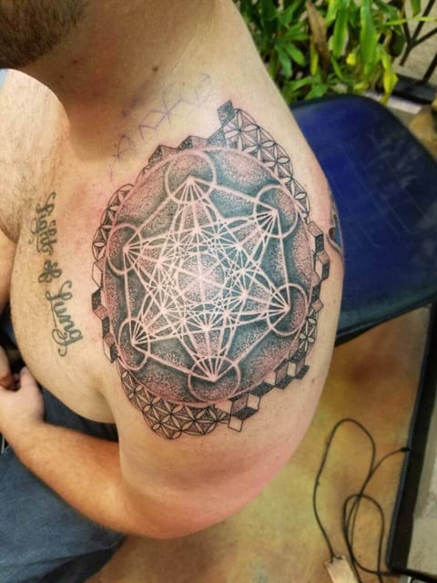 A black dotwork geometric mandala with interlocking lines covers a shoulder.