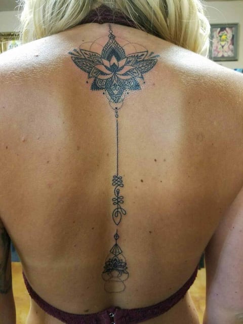 A black fine line lotus and ornamental line run down the center of a back.