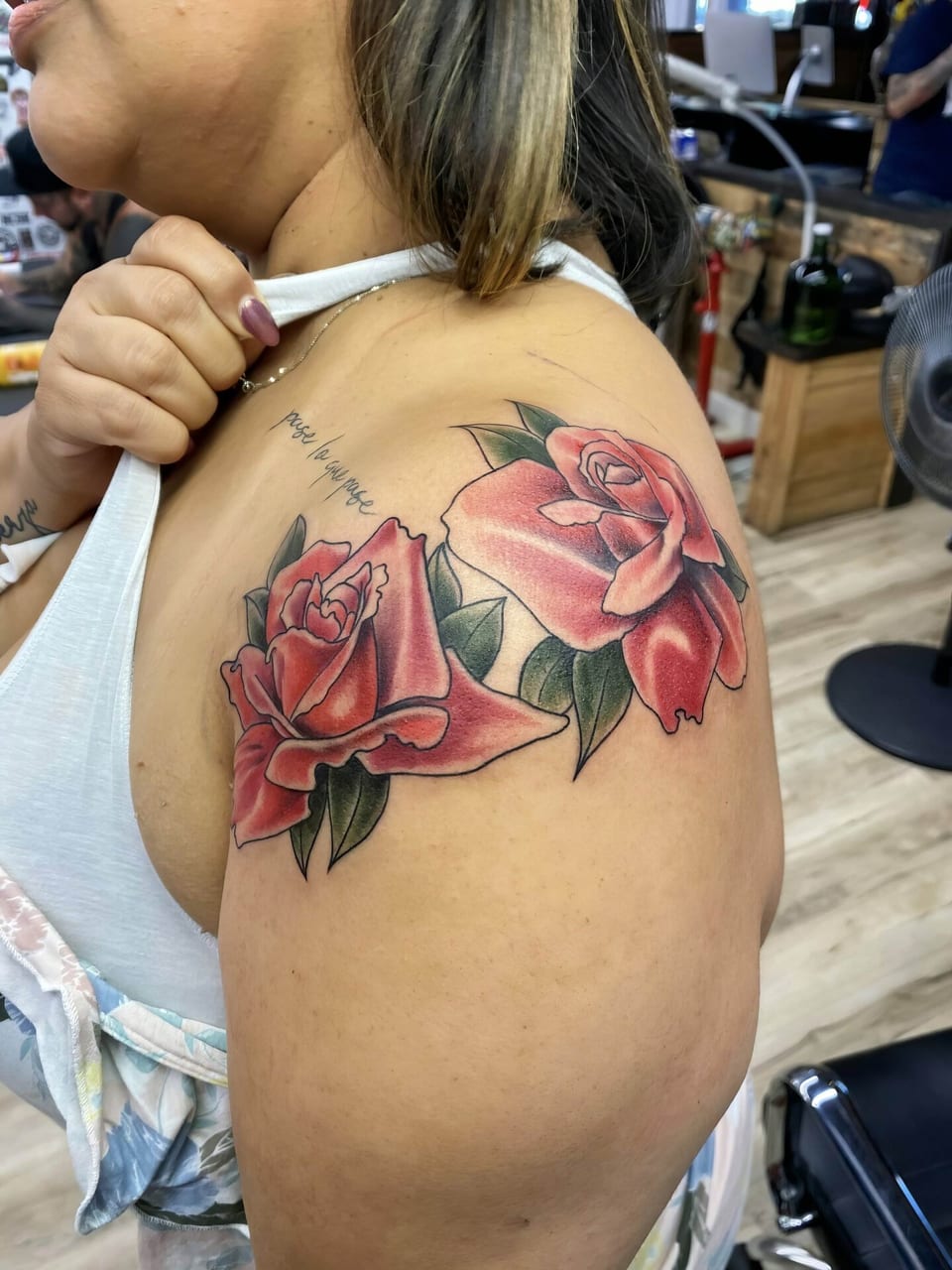 Color illustrative red roses with green leaves cover a shoulder and upper arm.